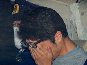 Takahiro Shiraishi covers his face in police custody during arrest