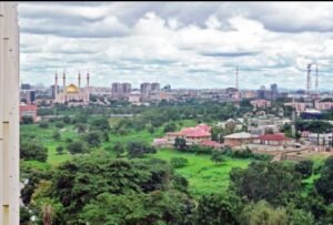 Nigerian government ; Aerial view of Abuja city skyline with prominent government buildings and greenery.