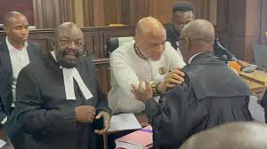 A courtroom scene featuring Mnadi Kanu interacting with lawyers during a trial session in Nigeria.