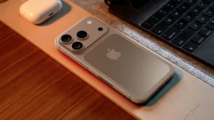 iPhone 17 Pro device placed on a desk beside a keyboard and AirPods.